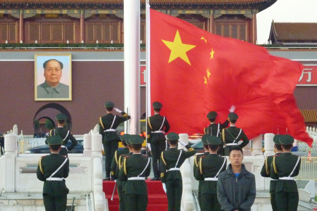 1949年以降の長期間にわたり、中央局のような組織の存在を通じて、中国の地方制度と国家戦略は高度な連動性を保ってきた、と著者は述べる。写真は北京の天安門に飾られている故毛沢東主席の肖像画と、国旗掲揚台の中国国旗。2012年10月26日(共同通信社)