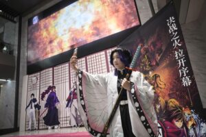 中国政府の「制裁」措置が外交カードになること自体、留学や旅行、ポップカルチャーを通じた日中間の文化交流がいかに浸透しているかを逆説的に示している。写真は「鬼滅の刃」が上映される北京の映画館で、記念撮影をするコスプレ姿の人。2025年11月14日（共同通信社）