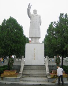 毛沢東が民兵に期待していた「階級闘争」は、宗族や集落間の抗争、あるいは略奪行為といった在地的な要素を内包した形で展開されていたとも言えよう。写真は、社会主義農村として知られる河南省・南街村の広場に建つ真っ白な毛沢東像と、その傍らで歩哨に立つ民兵。2006年8月30日（共同通信社）