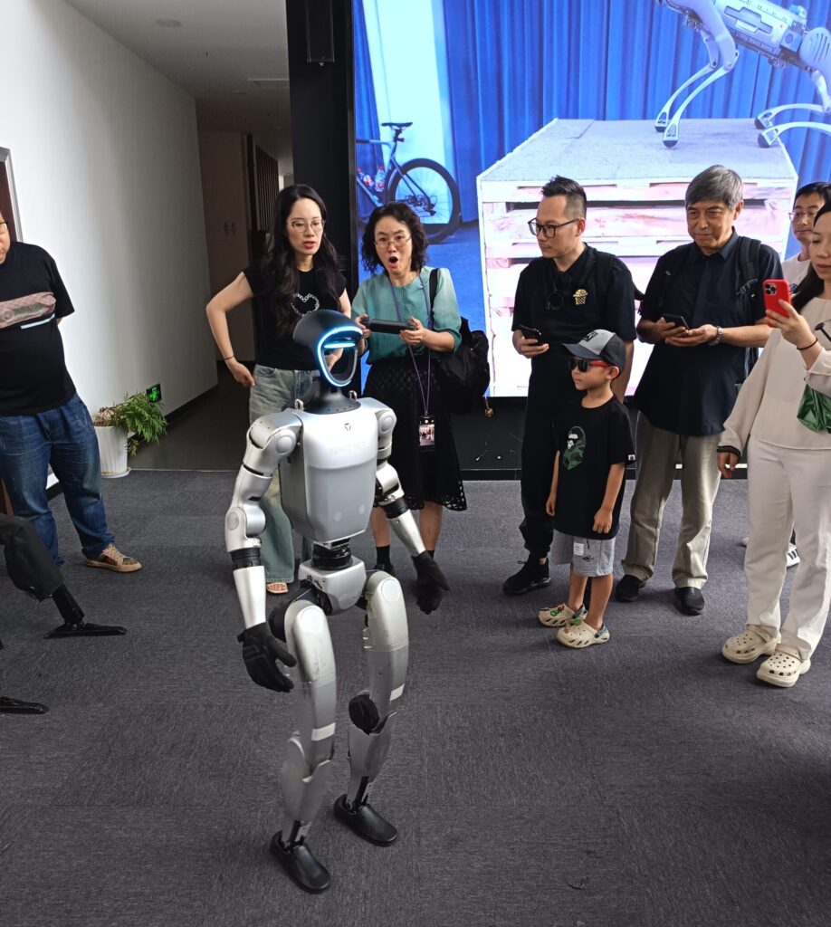 地方政府が実施している産業振興の方策として特に効果的だとみられるのが、同業や関連業種の企業を誘致して産業クラスターを形成する政策である。写真は杭州市の宇樹科技（Unitree）の本社で、ヒト型ロボットを操作して驚く人たち。2025年8月25日（著者撮影・提供、以下も同じ）