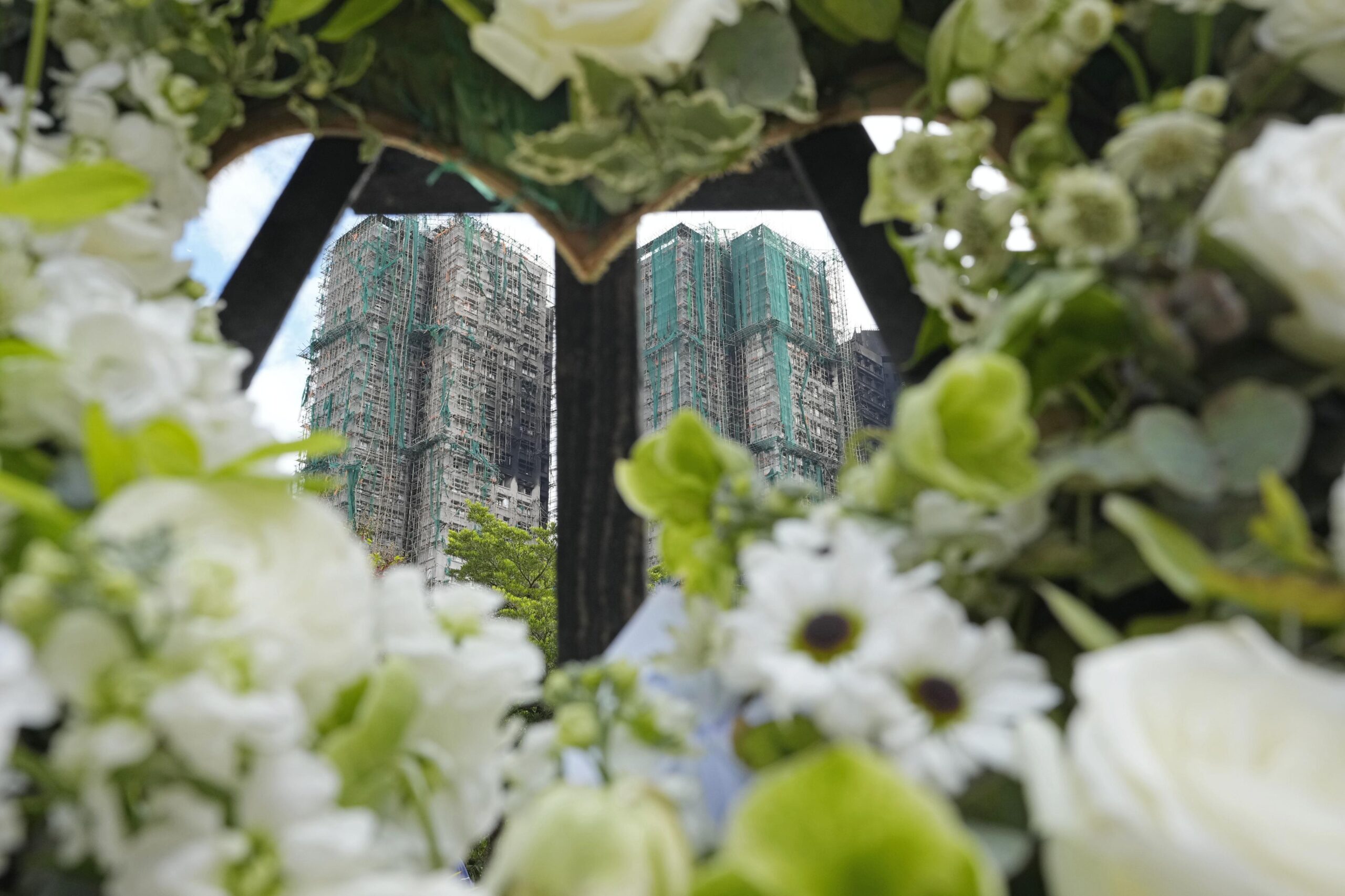 必要な安全対策が実現しなかった原因の一つを、人々はコンサルタント会社、修繕請負業者、マンション管理組合の理事会、管理会社などによる結託に求めている。写真は火災が起きた高層住宅群近くに手向けられた花。2025年12月2日（共同通信社）