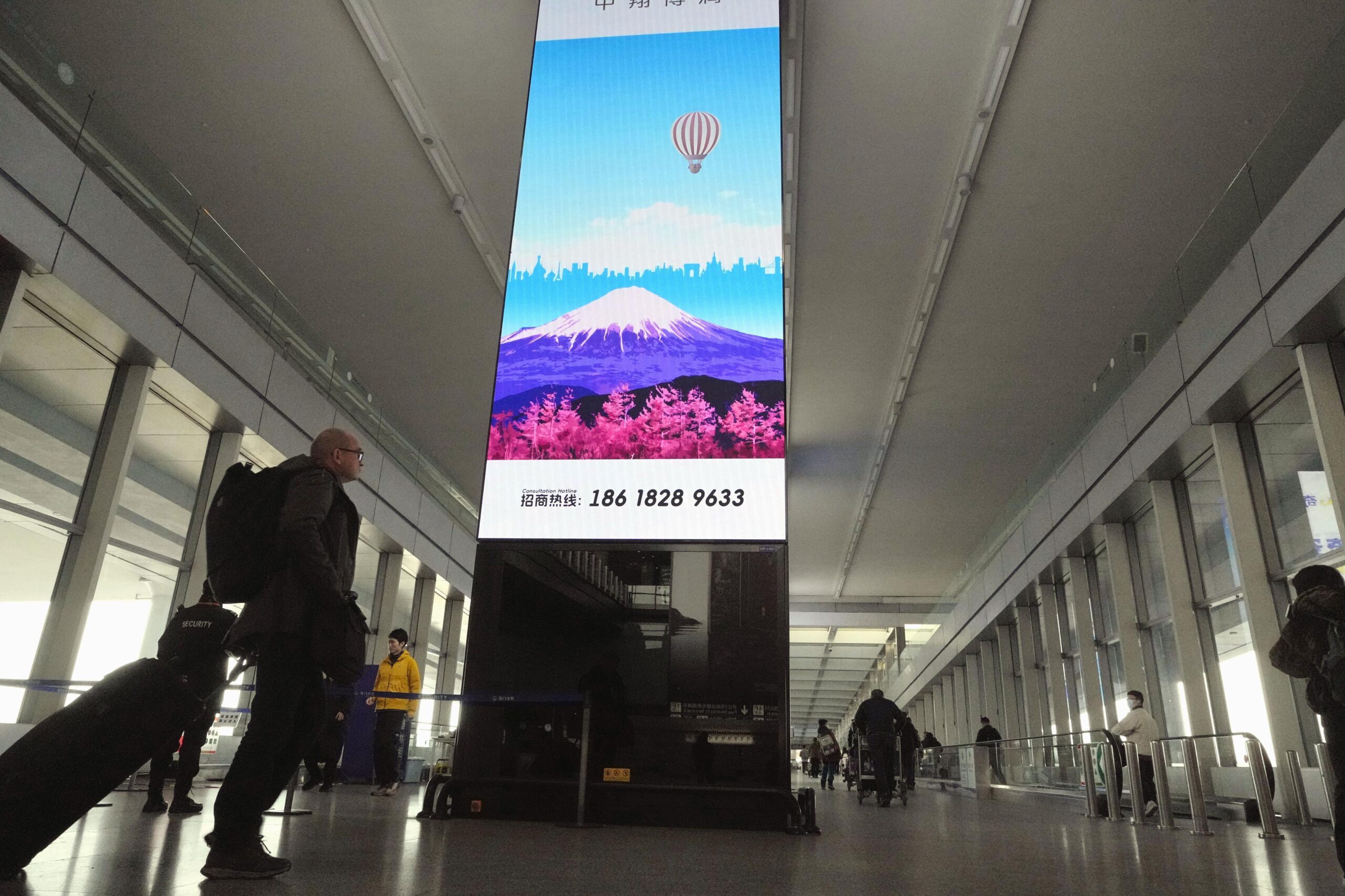 日中関係は「低強度の対立」を特徴とする一種の「新常態（ニューノーマル）」へと移行しつつある可能性がある。写真は中国政府による日本渡航自粛の呼びかけから約1カ月となる北京首都国際空港で、大型画面に表示された富士山のイラスト。2025年12月13日（共同通信社）